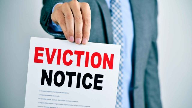 person-in-a-business-suit-holding-up-a-paper-with-the-word-eviction-notice person-in-a-business-suit-holding-up-a-paper-with-the-word-eviction-notice